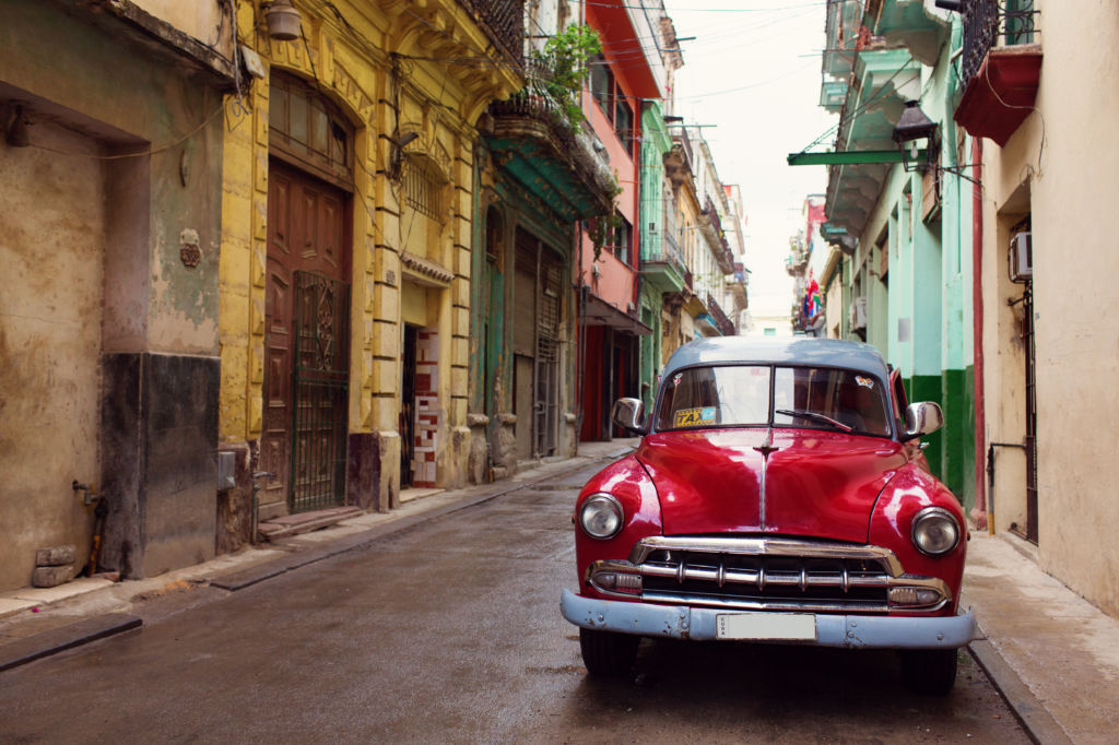 Coche rojo clásico en las calles coloridas de La Habana, en Cuba