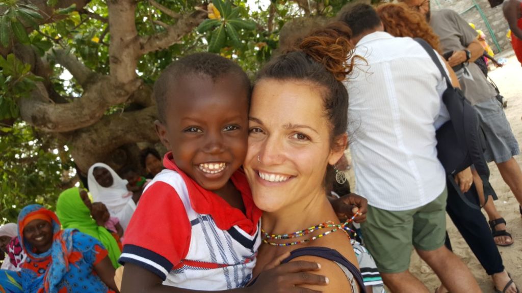Mujer con niño africano en los brazos, sonriendo ambos