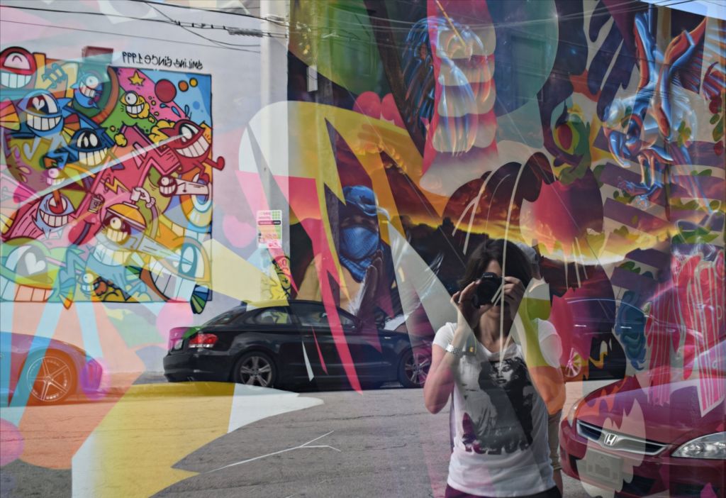 Reflejo sobre una vitrina colorida de una mujer con una cámara de fotos tapándole la cara