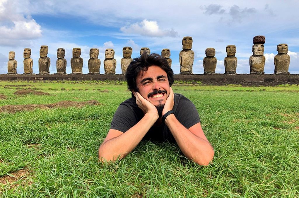 Hombre sobre el césped con las estatuas de la Isla de Pascua detrás